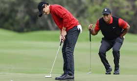 In the well-known Sunday red, Tiger Woods and his son Charlie tee off in perfect symmetry.